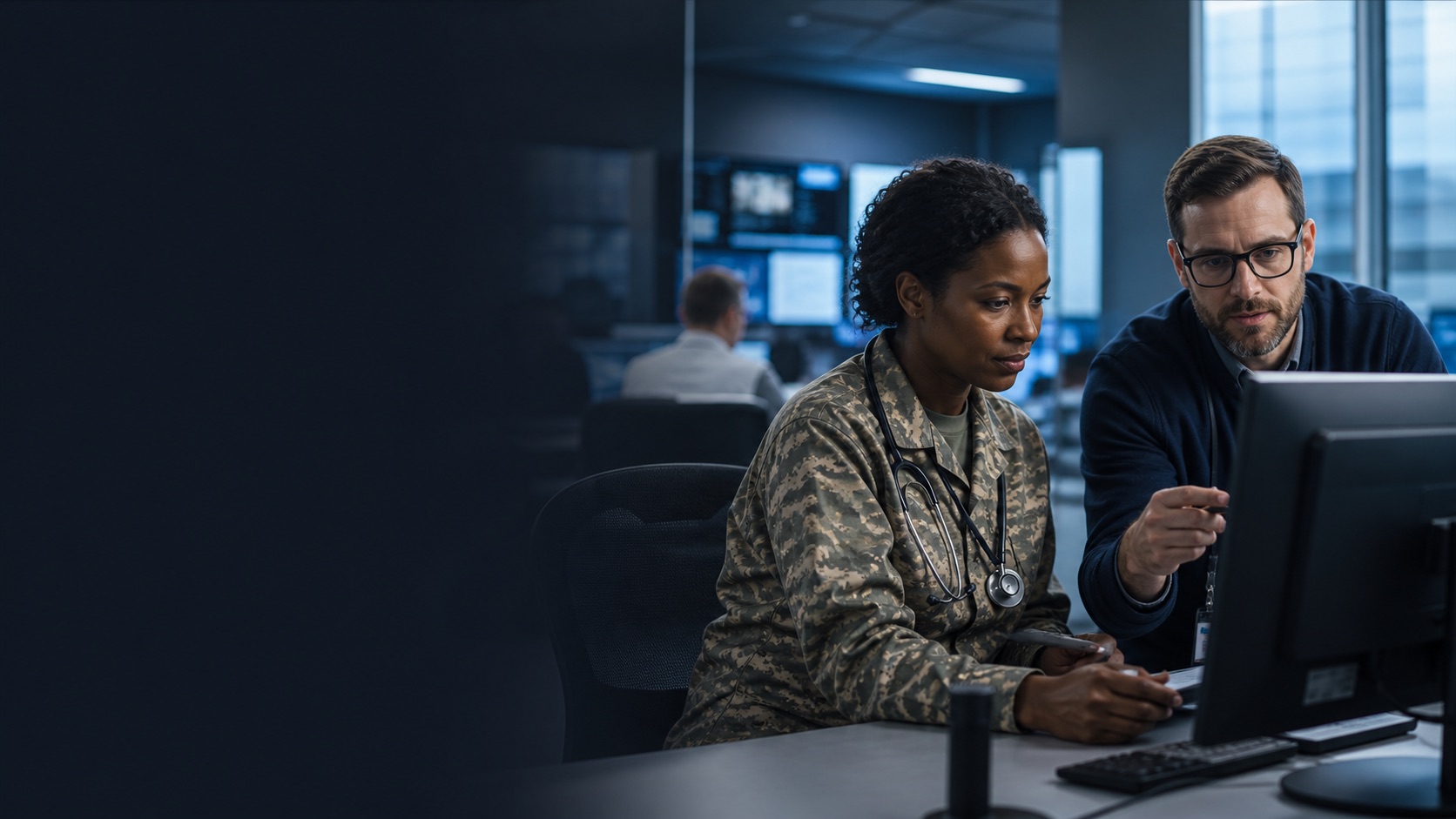 Military medical professional and technology specialist reviewing a clinical system